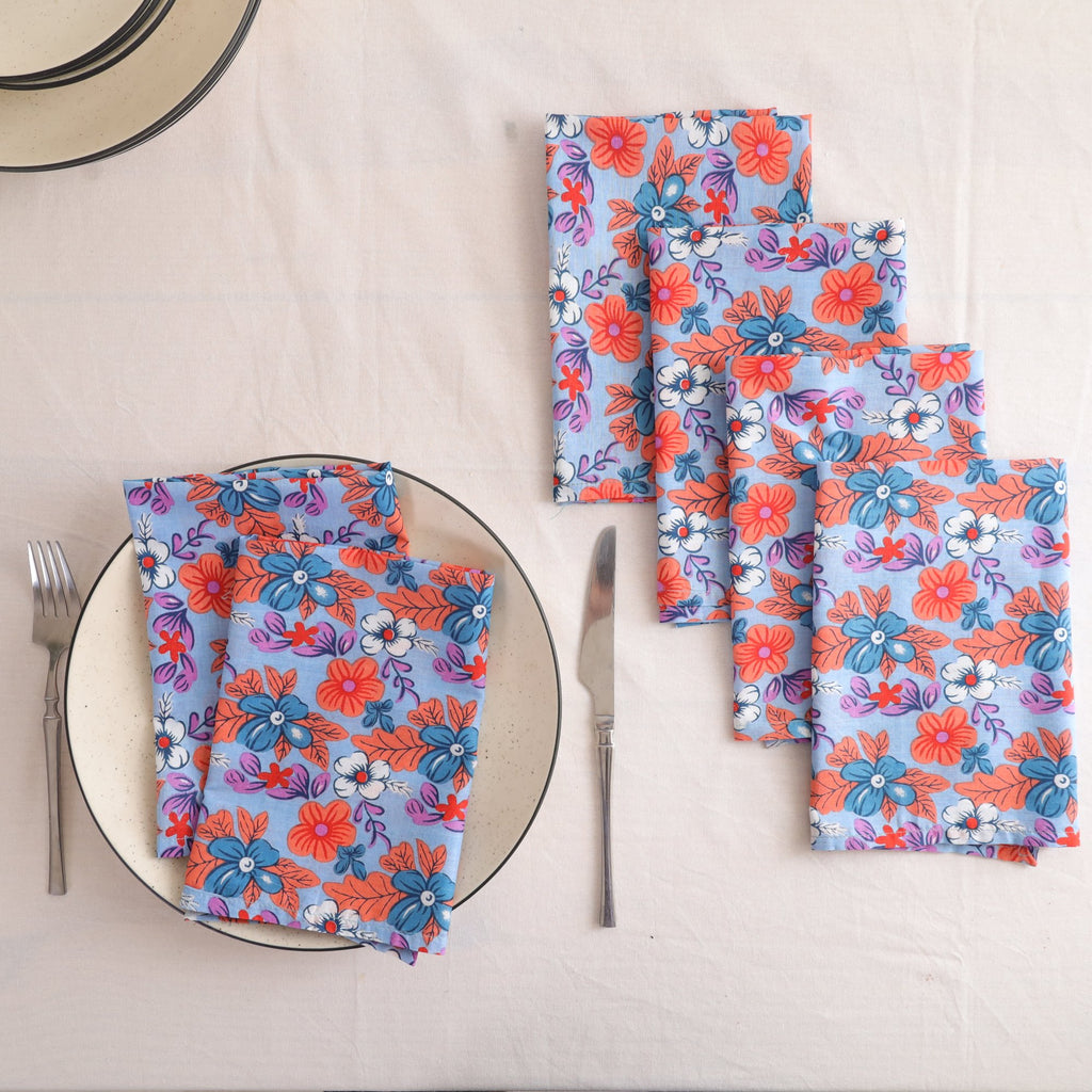 Set of four blue and coral block print cotton napkins fanned out on a laid table