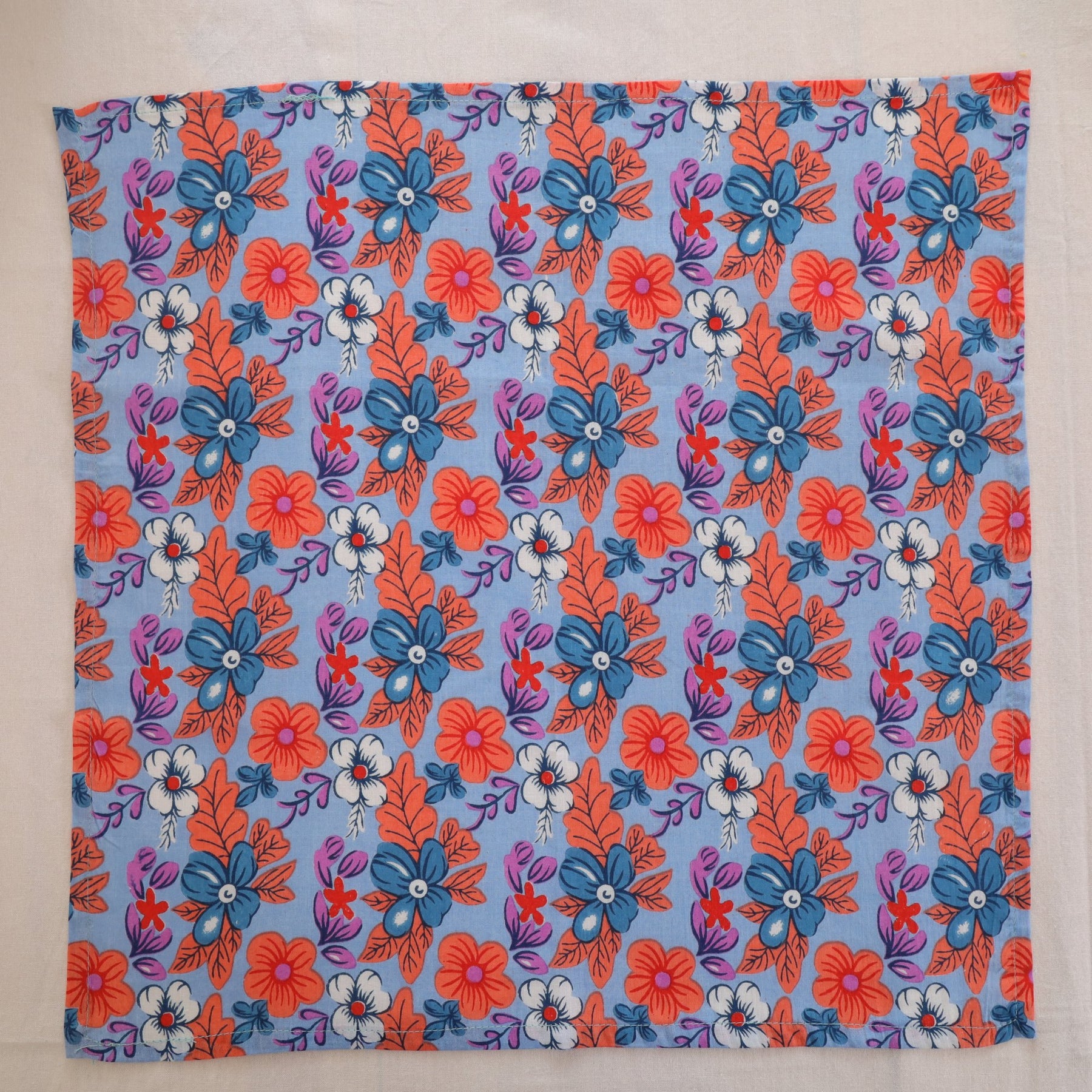 Blue and coral hand block print cotton napkin laid flat, full print visible
