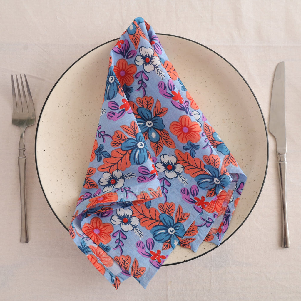 Blue and coral block print cotton napkin folded on a dinner plate
