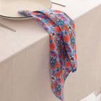 Blue and coral block print napkin draped over the edge of a table