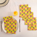 Set of four yellow and pink block print cotton napkins fanned out on a laid table