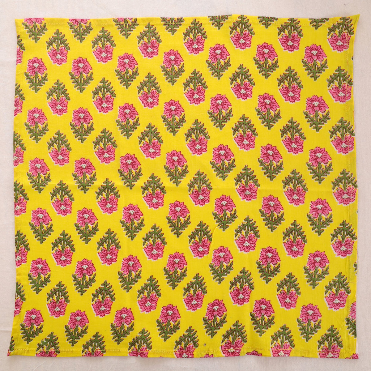 Yellow and pink hand block print cotton napkin laid flat, full print visible