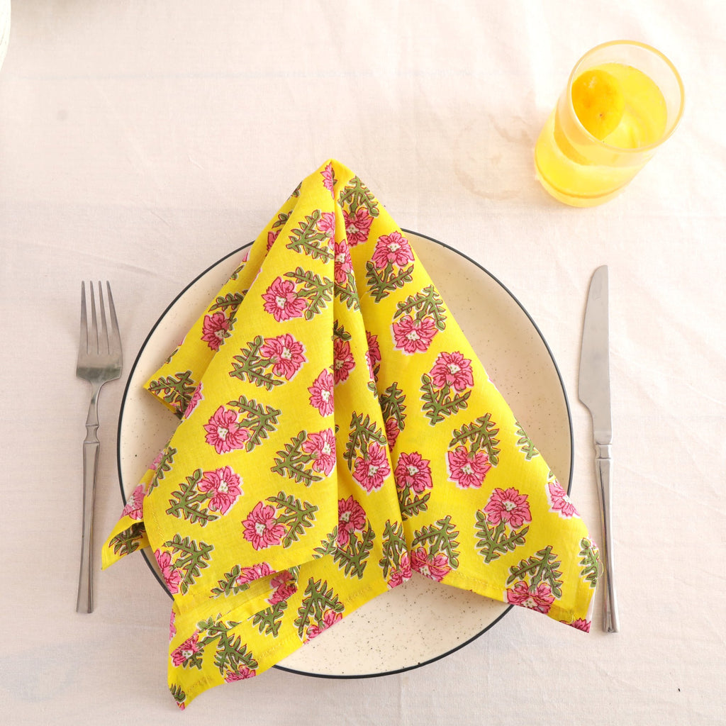Yellow and pink block print cotton napkin folded on a dinner plate