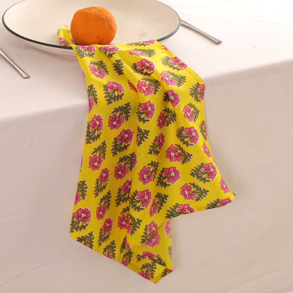 Yellow and pink block print napkin draped over the edge of a table