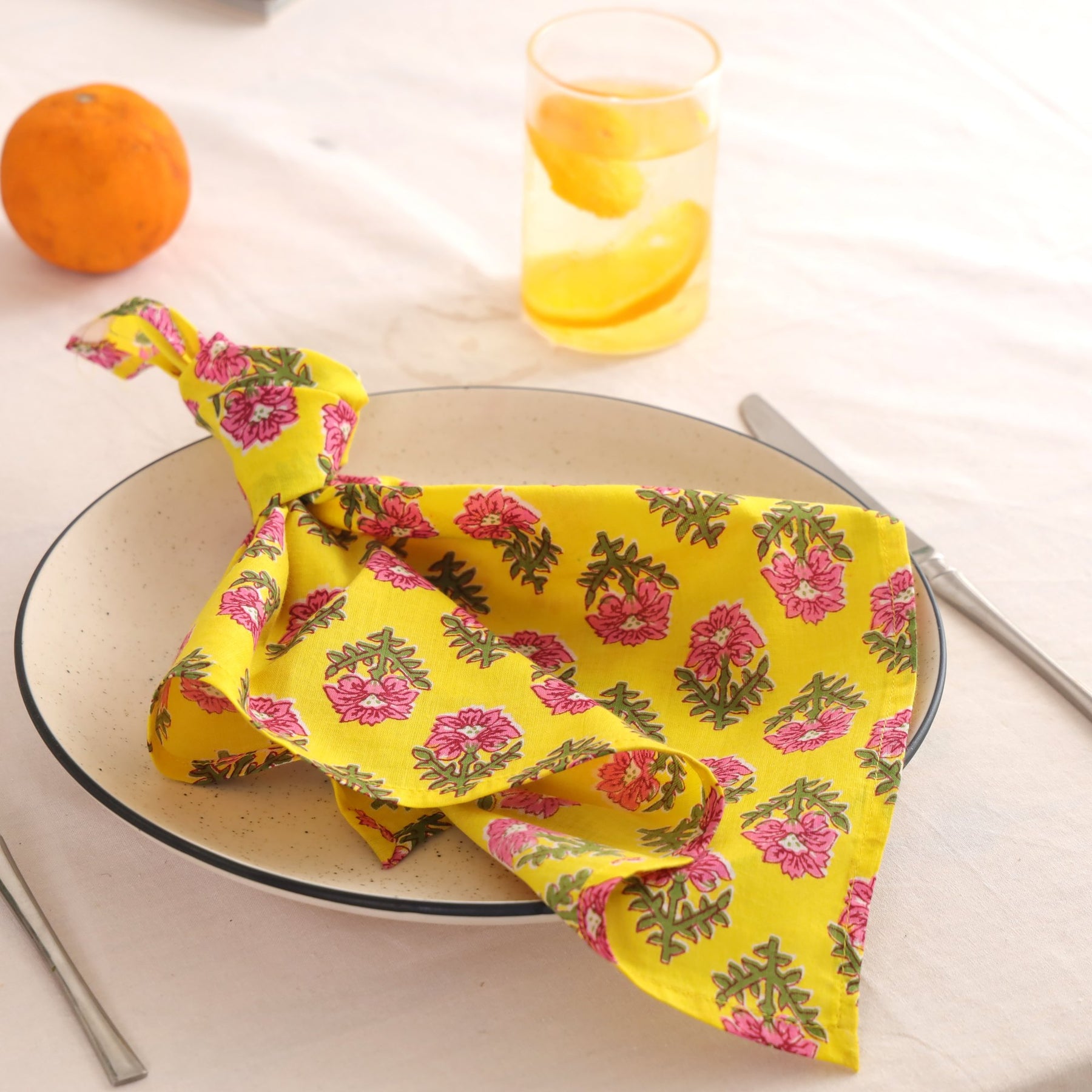 Yellow and pink block print cotton napkin knotted on a plate