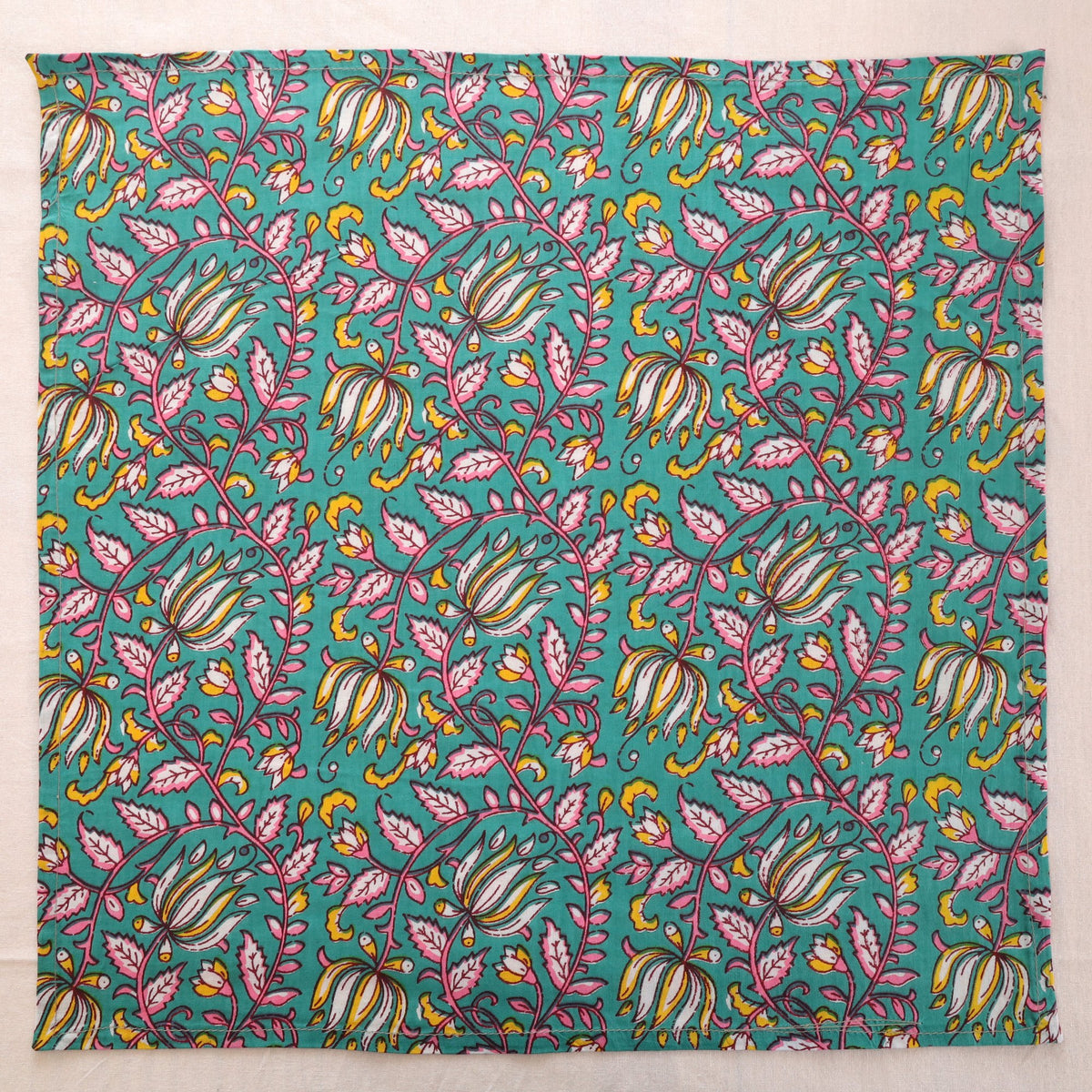 Teal and pink hand block print cotton napkin laid flat, full print visible