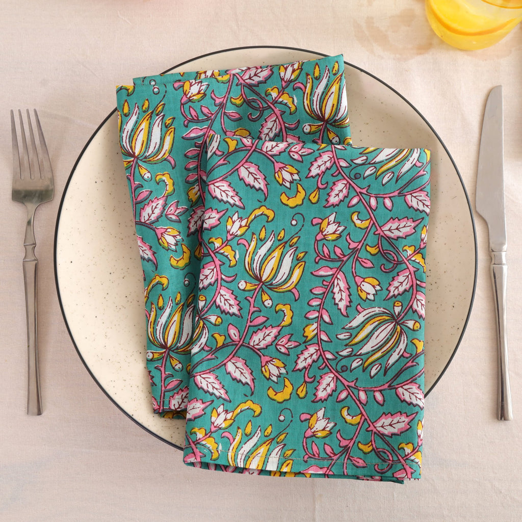 Teal and pink block print cotton napkin folded on a dinner plate