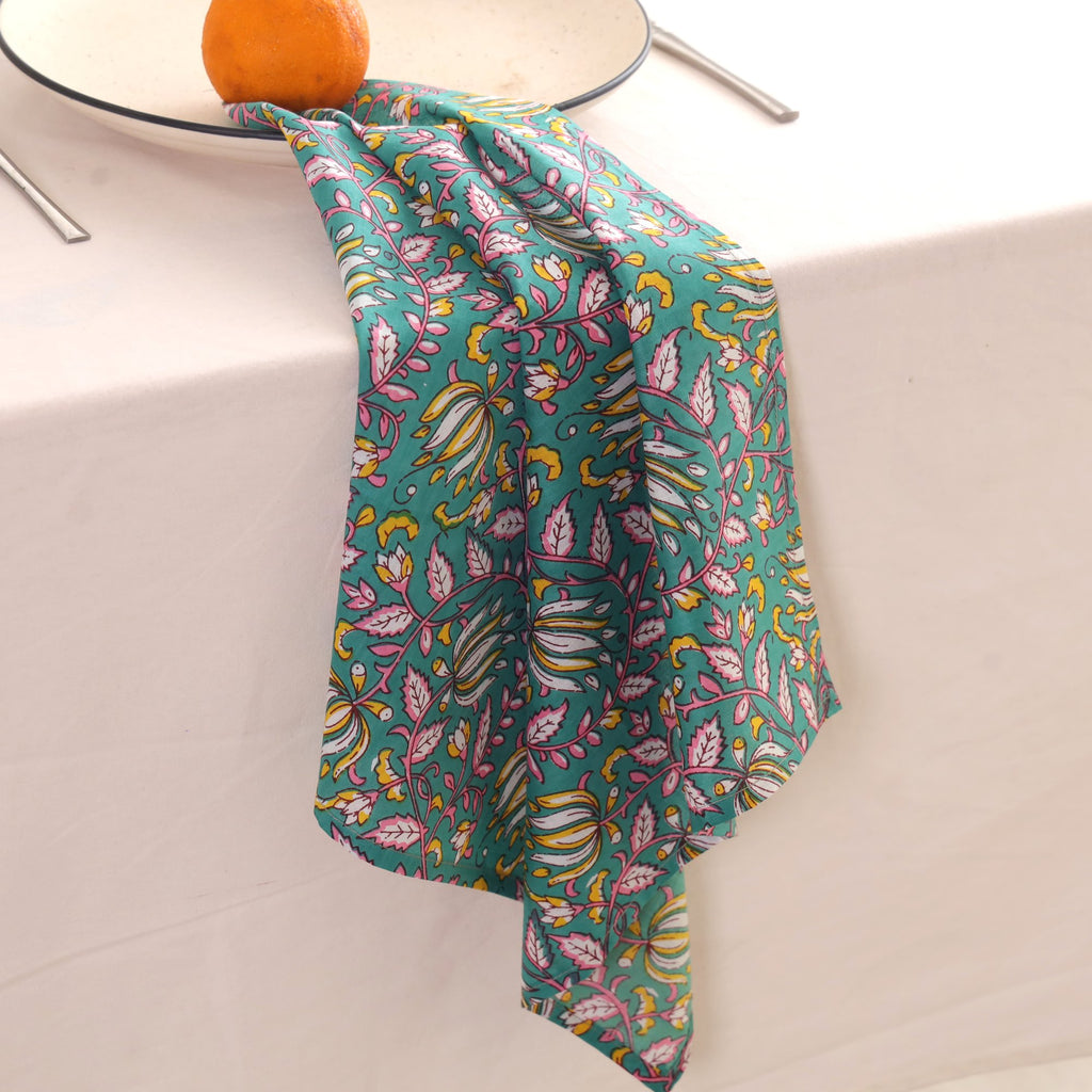 Teal and pink block print napkin draped over the edge of a table