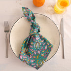 Teal and pink block print cotton napkin knotted on a plate