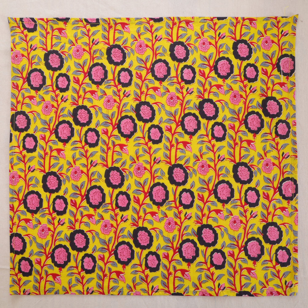 Chartreuse and pink hand block print cotton napkin laid flat, full print visible