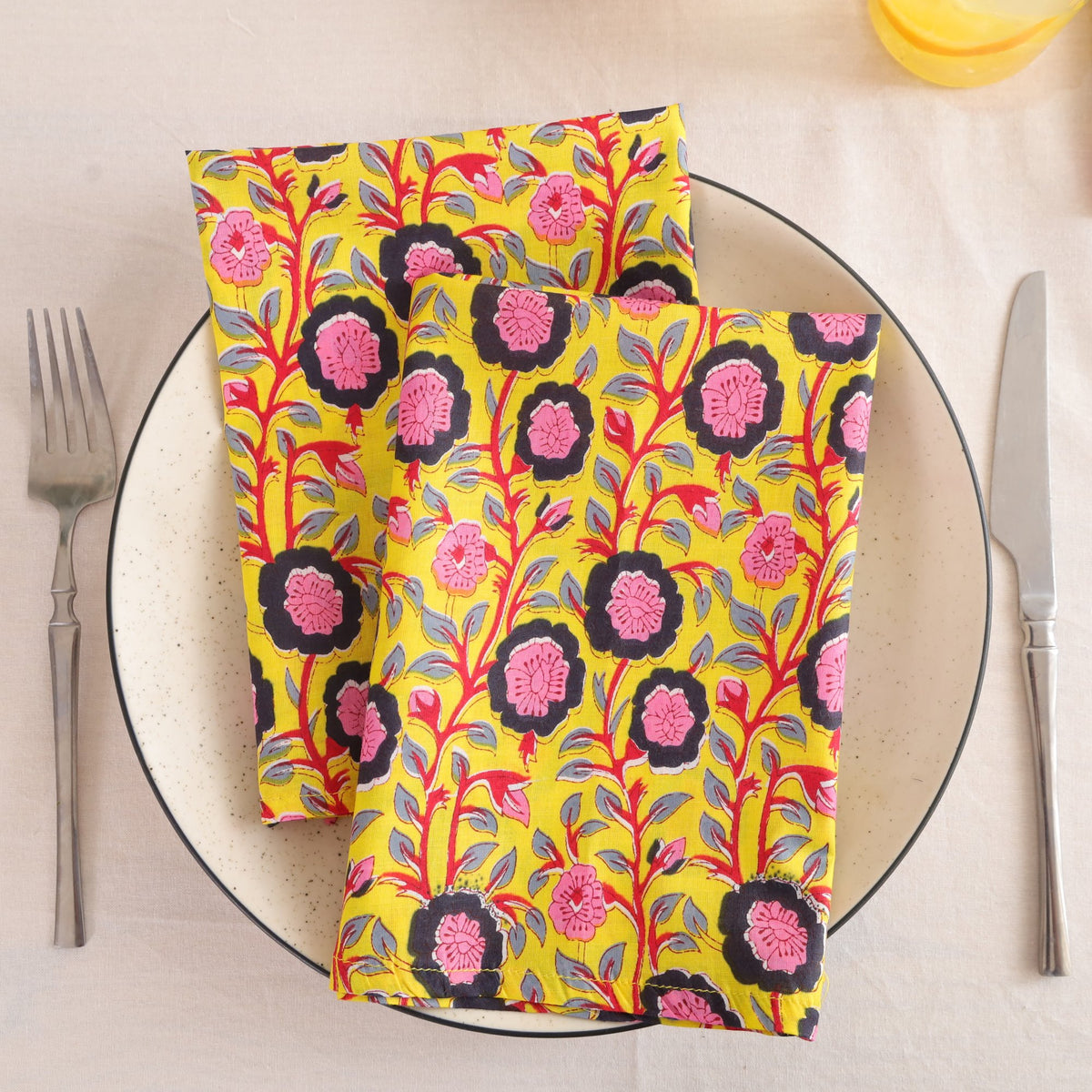 Chartreuse and pink block print cotton napkin folded on a dinner plate