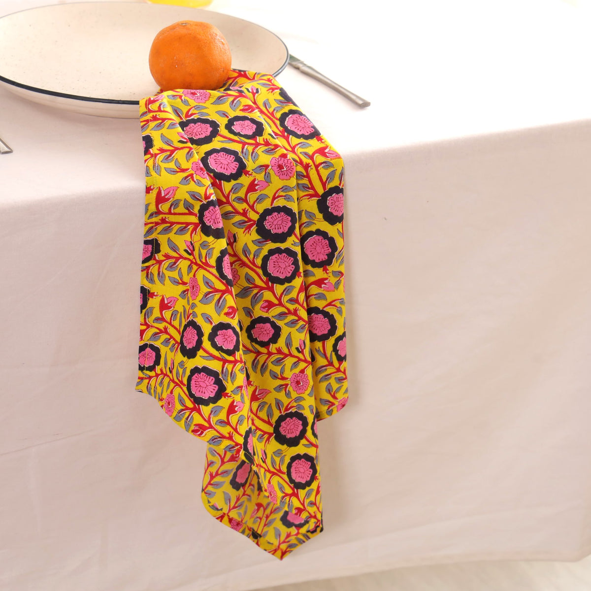 Chartreuse and pink block print napkin draped over the edge of a table