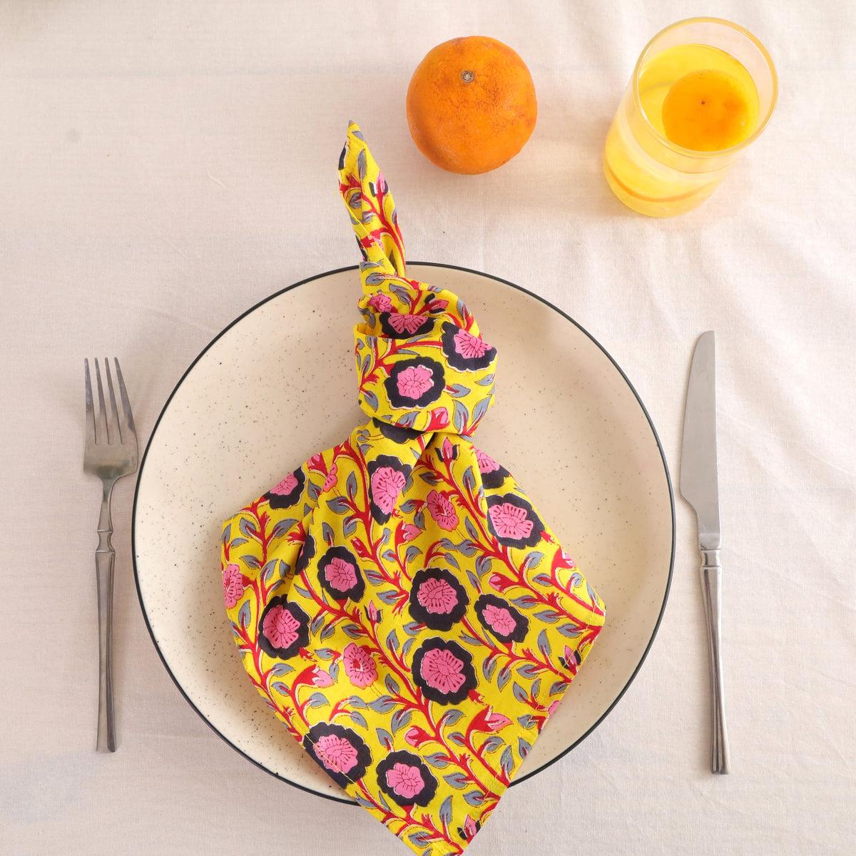 Chartreuse and pink block print cotton napkin knotted on a plate