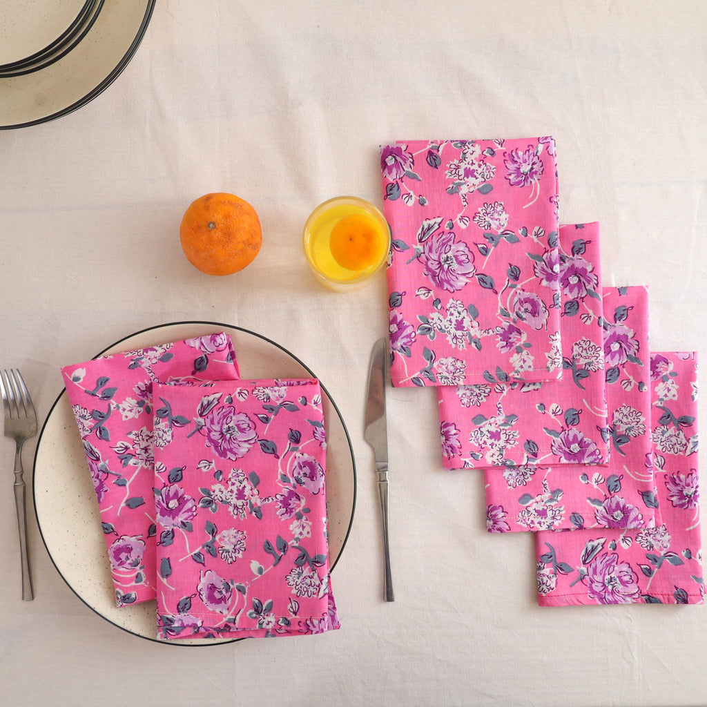 Set of four pink and purple block print cotton napkins fanned out on a laid table