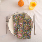 Olive and pink block print cotton napkin folded on a dinner plate