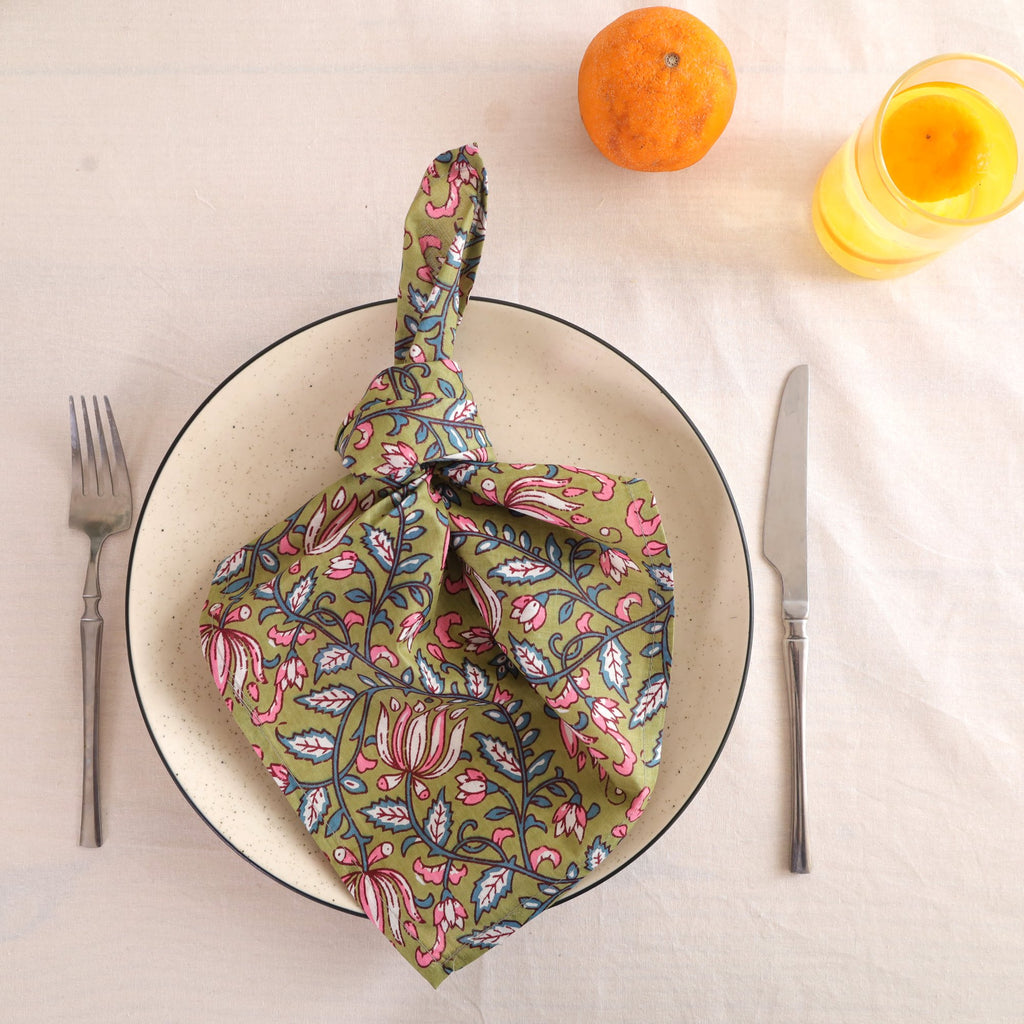 Olive and pink block print cotton napkin knotted on a plate