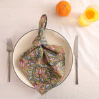 Olive and pink block print cotton napkin knotted on a plate