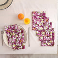 Set of four purple and white block print cotton napkins fanned out on a laid table