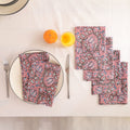 Set of four dusty rose block print cotton napkins fanned out on a laid table