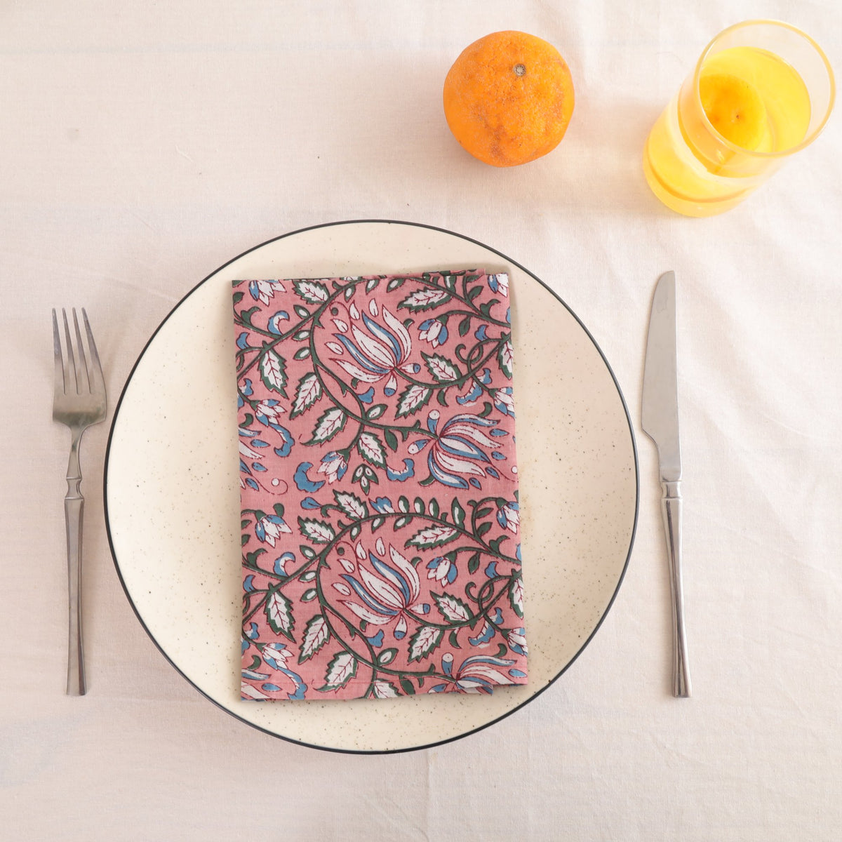 Dusty rose block print cotton napkin folded on a dinner plate