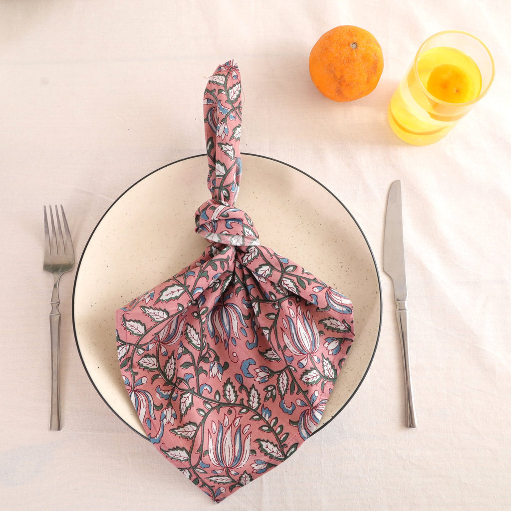Dusty rose block print cotton napkin knotted on a plate