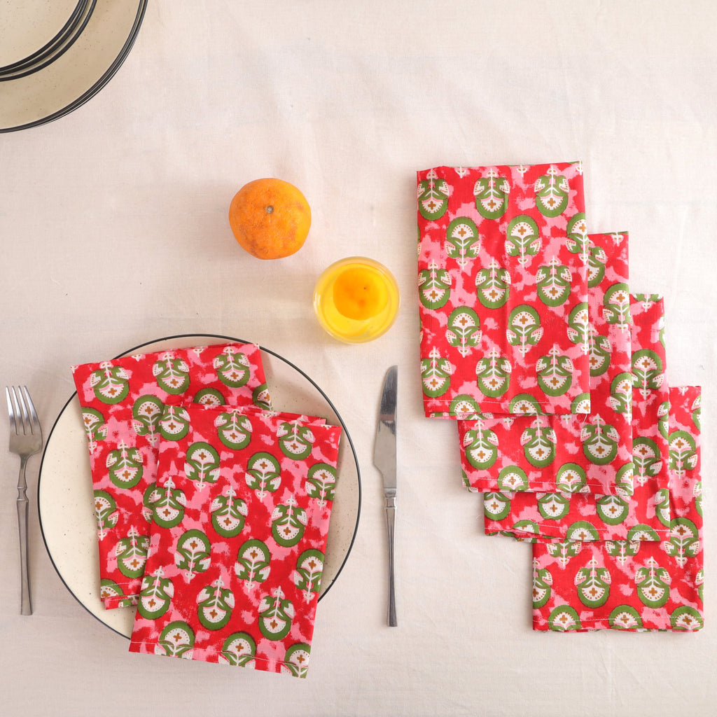 Set of four red and green block print cotton napkins fanned out on a laid table