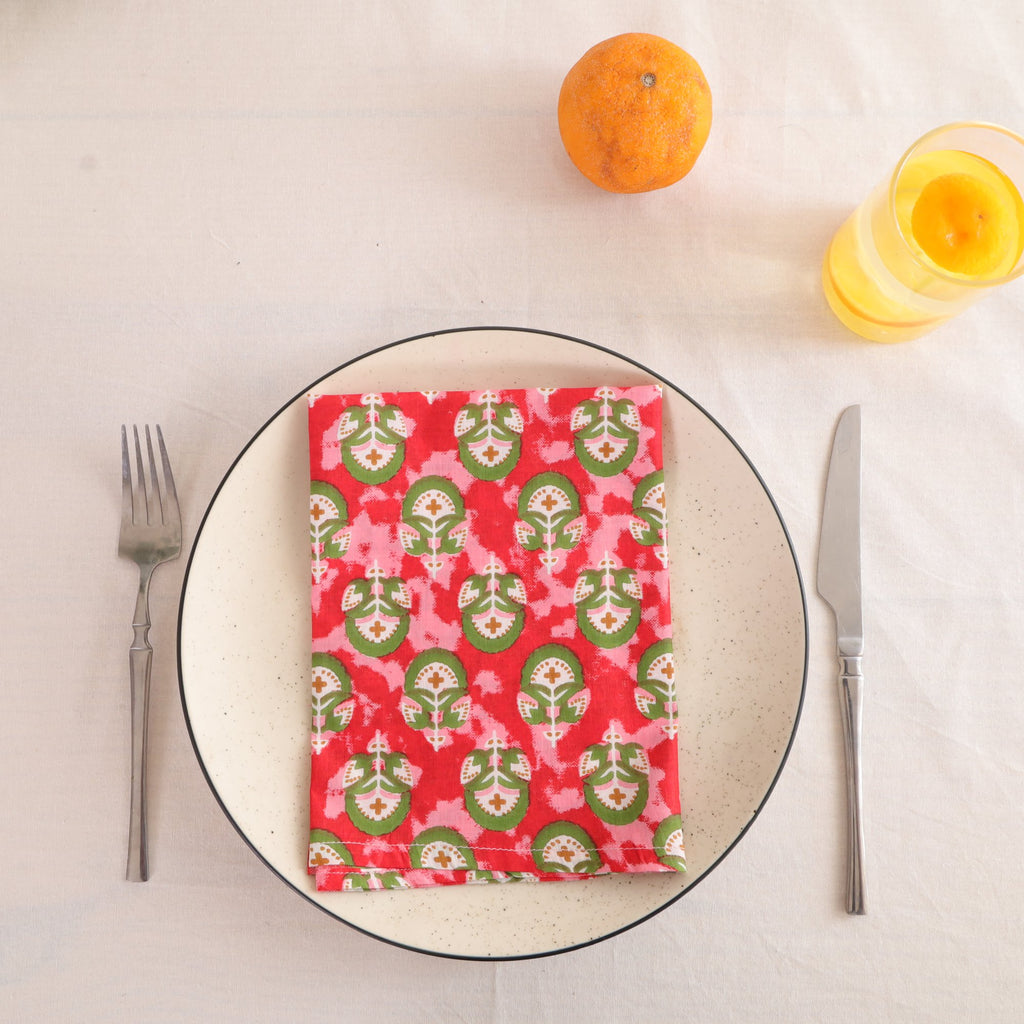 Red and green block print cotton napkin folded on a dinner plate
