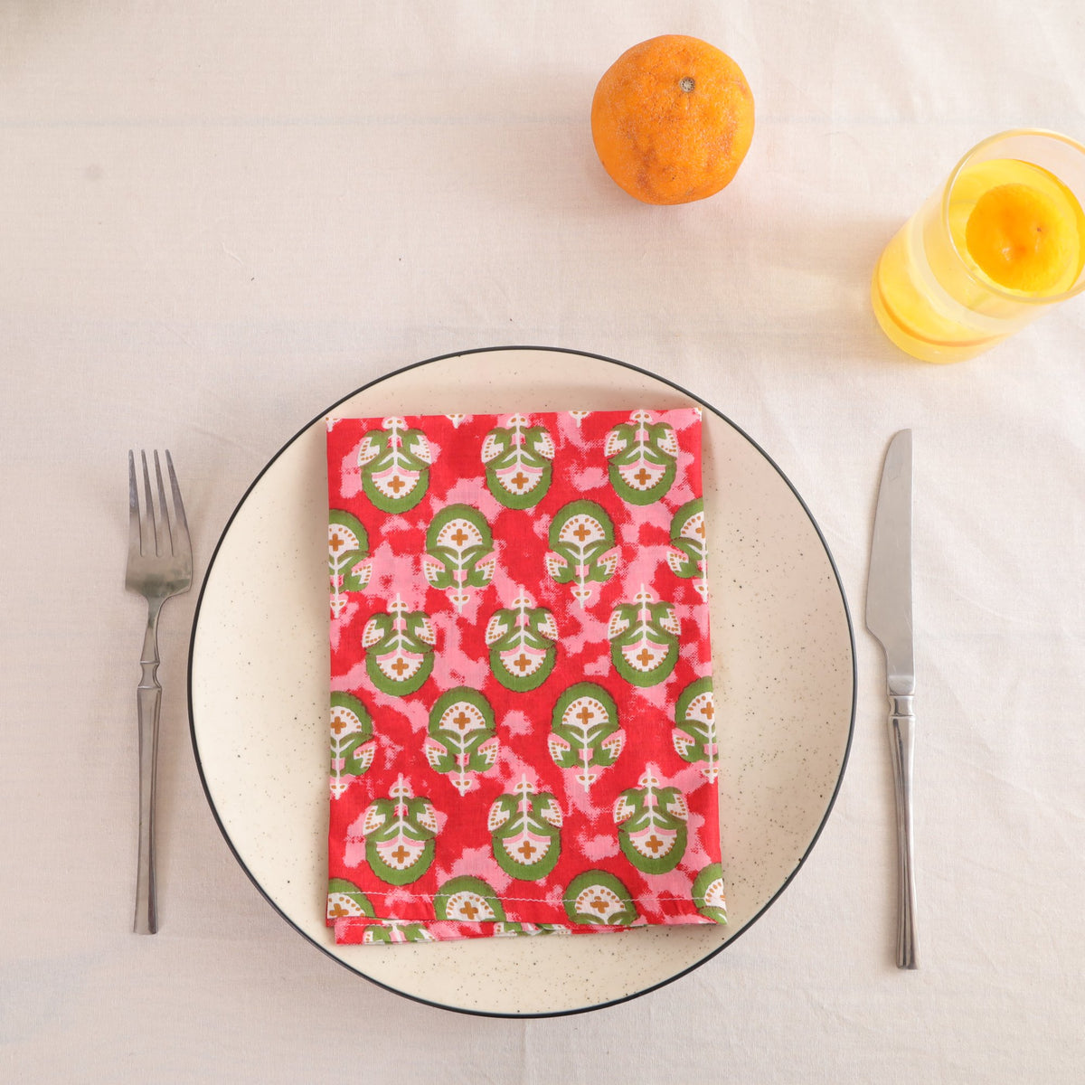Red and green block print cotton napkin folded on a dinner plate