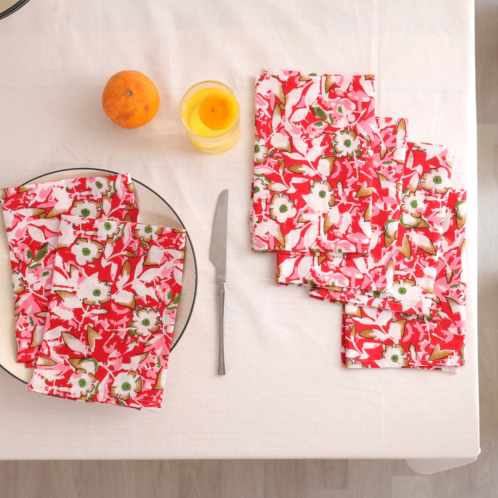 Set of four red and cream block print cotton napkins fanned out on a laid table