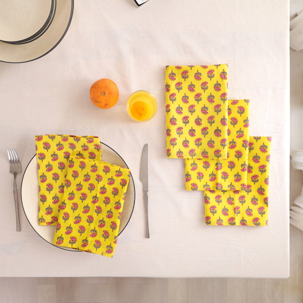 Set of four yellow buti block print cotton napkins fanned out on a laid table