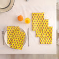 Set of four yellow buti block print cotton napkins fanned out on a laid table