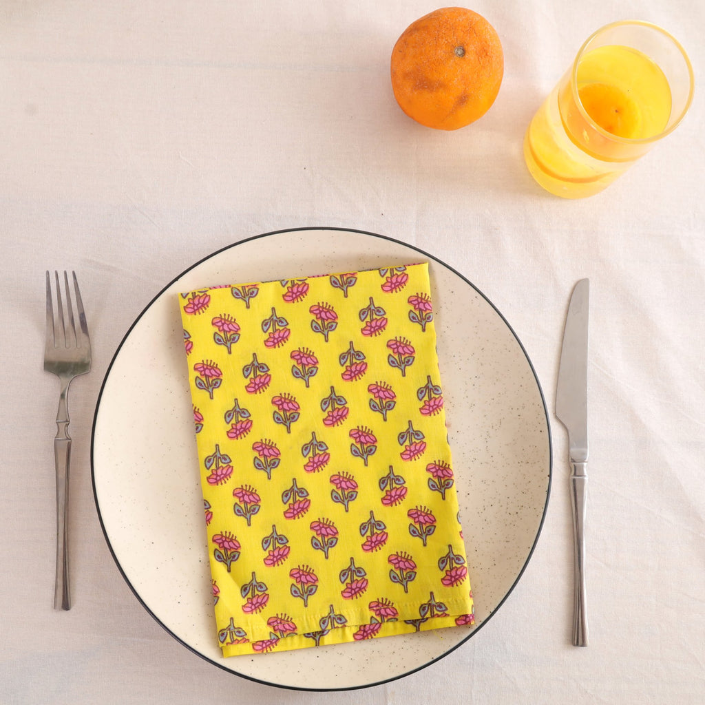 Yellow buti block print cotton napkin folded on a dinner plate