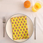 Yellow buti block print cotton napkin folded on a dinner plate