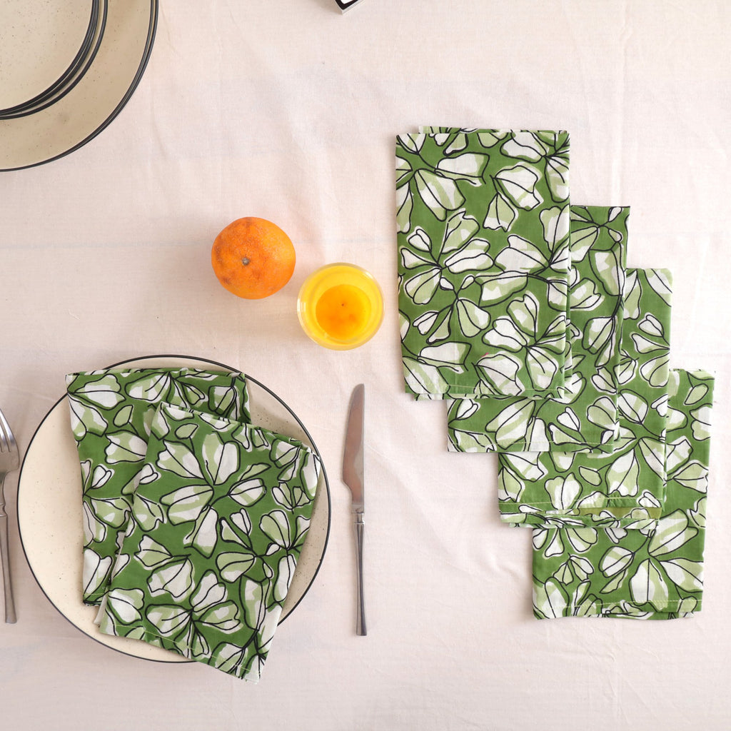 Set of four green and white block print cotton napkins fanned out on a laid table