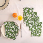 Set of four green and white block print cotton napkins fanned out on a laid table