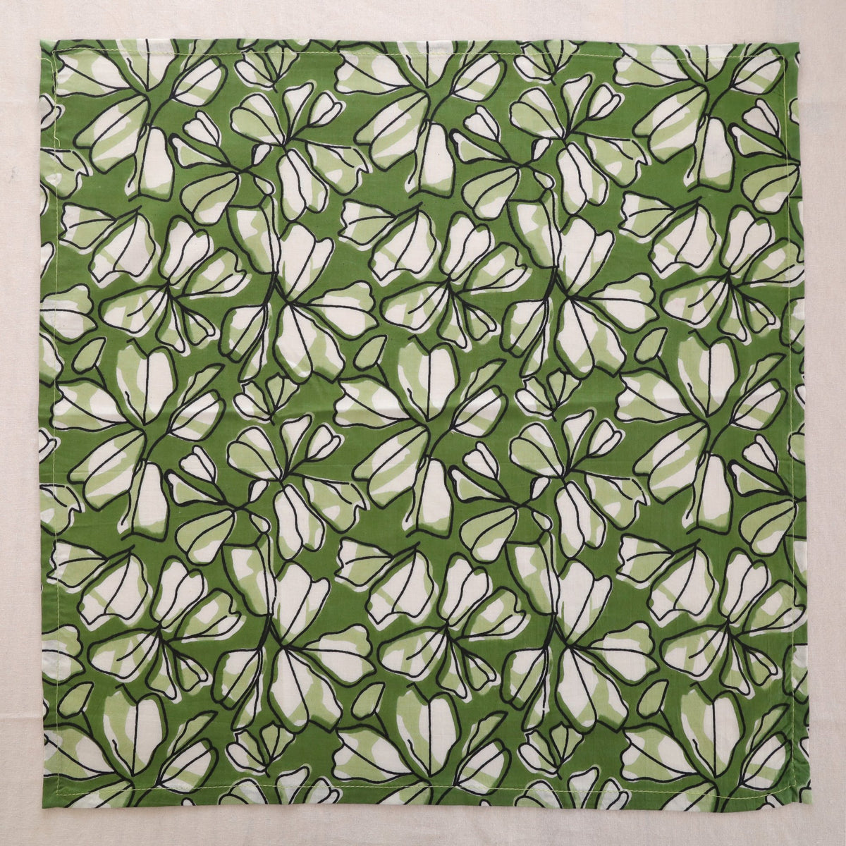Green and white hand block print cotton napkin laid flat, full print visible