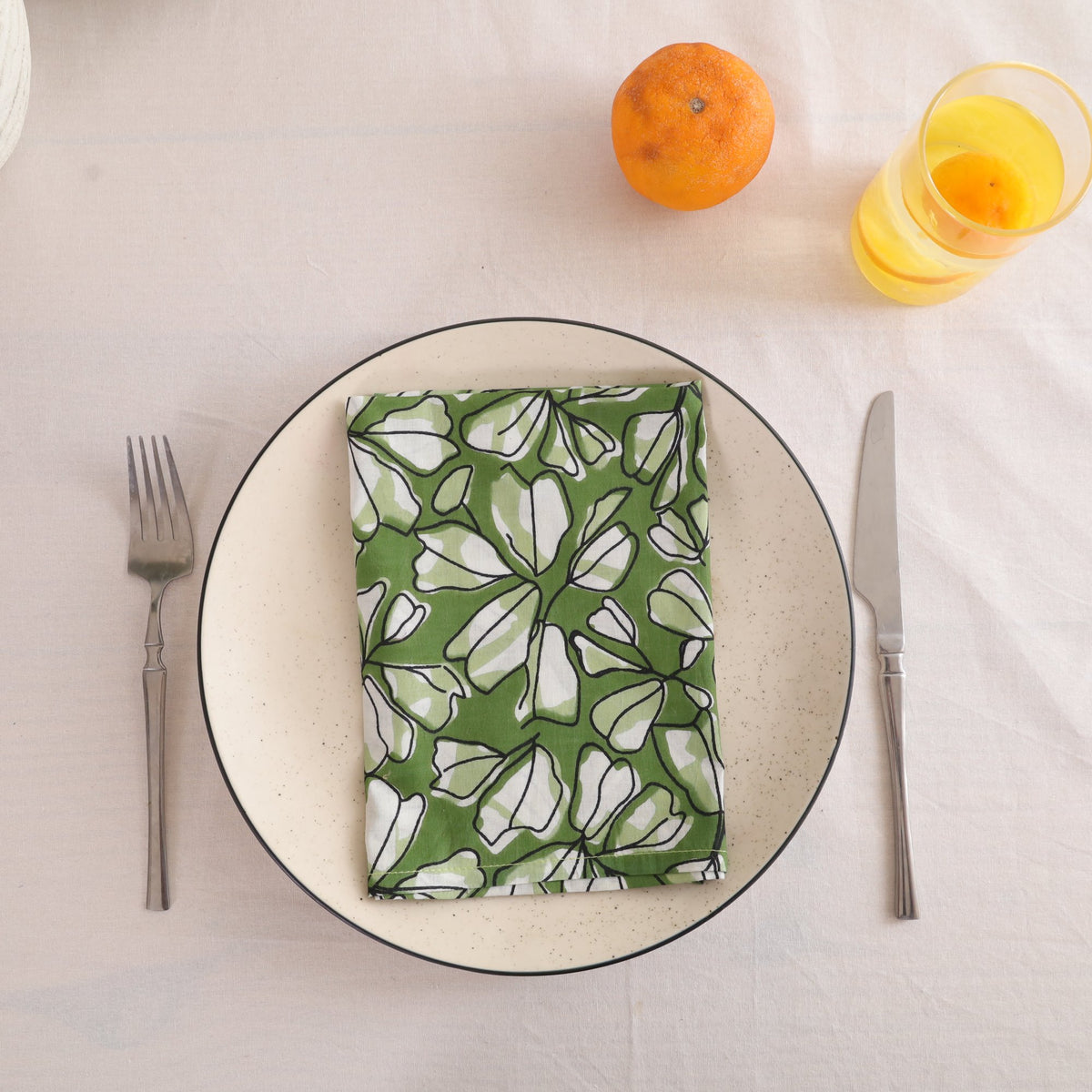 Green and white block print cotton napkin folded on a dinner plate
