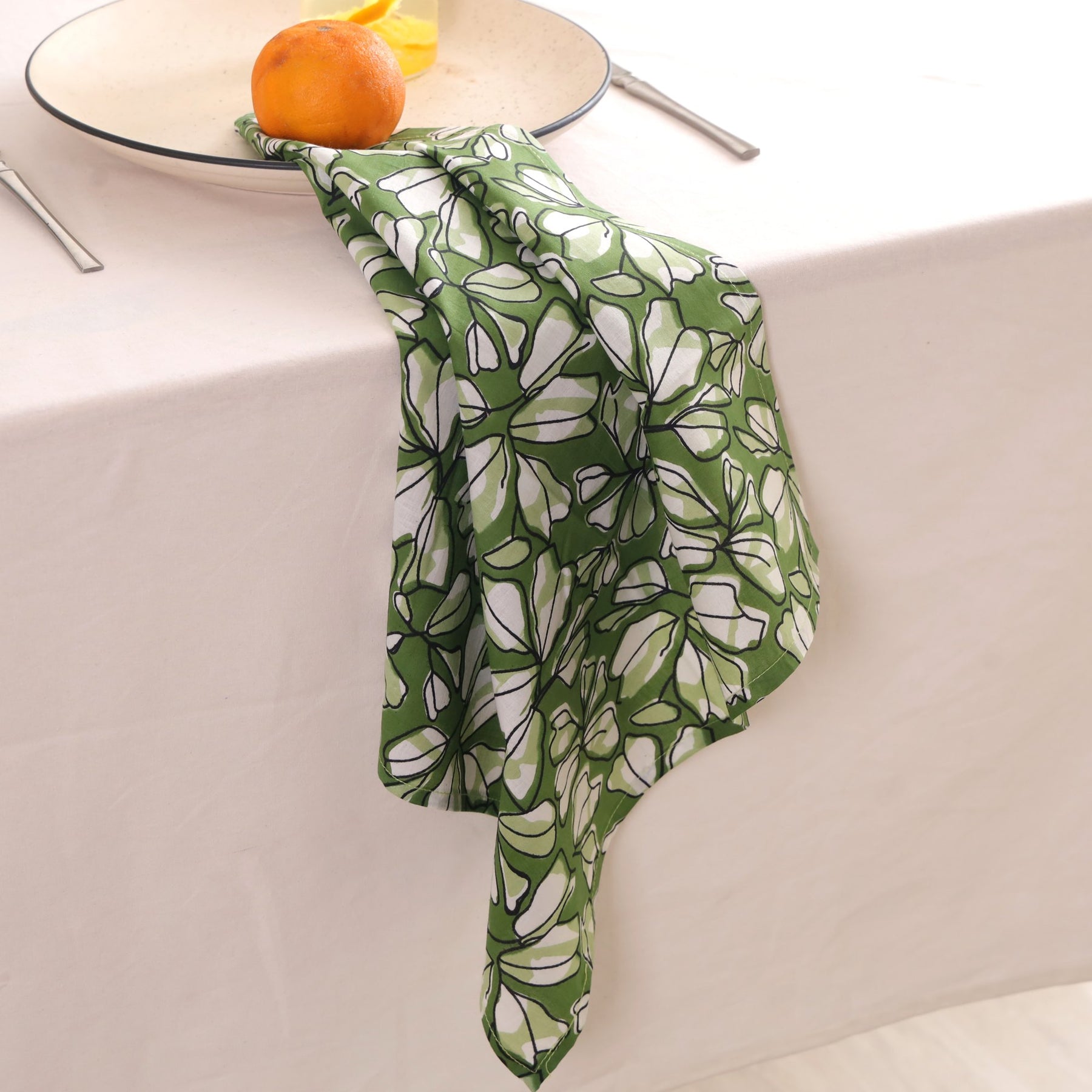Green and white block print napkin draped over the edge of a table