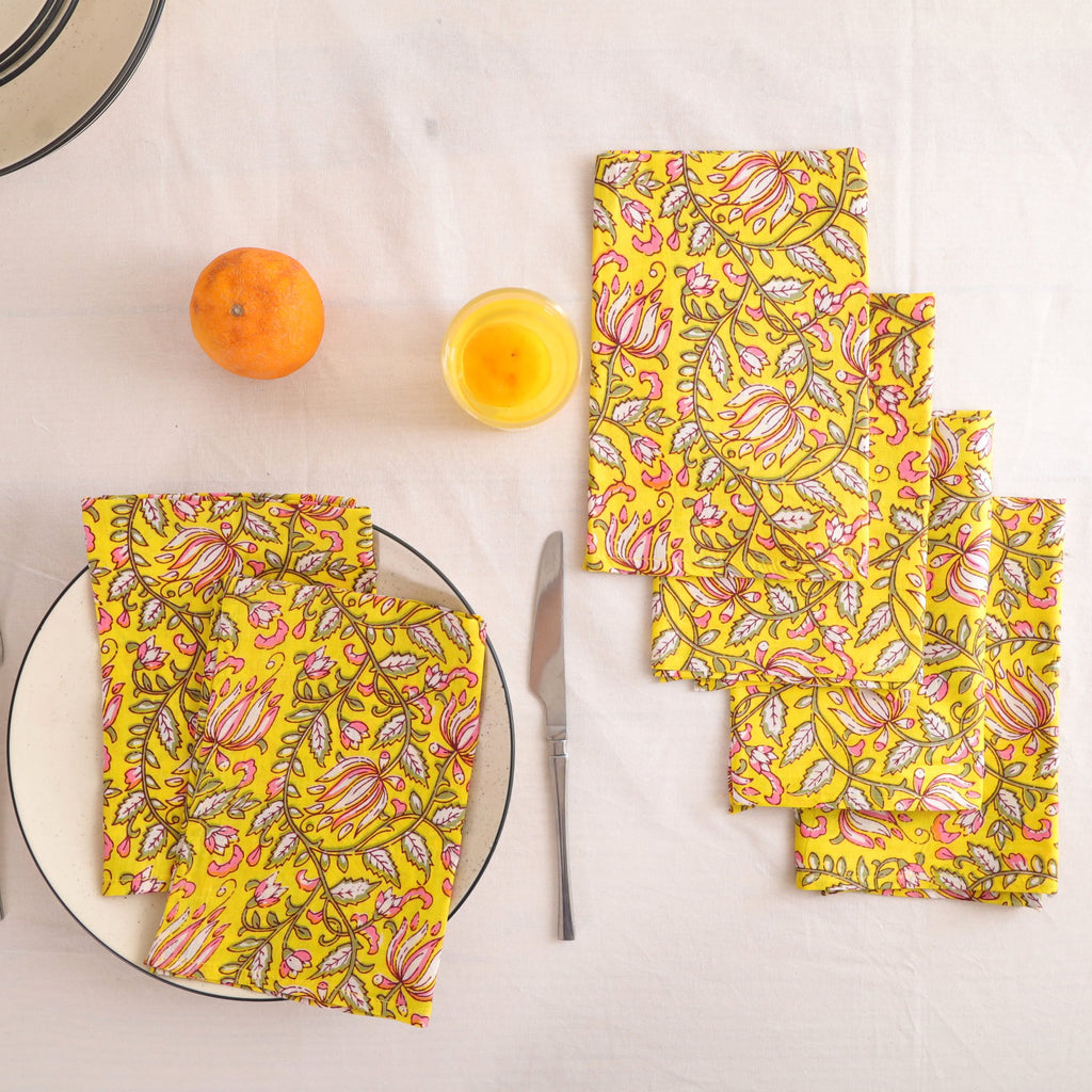 Set of four yellow and pink block print cotton napkins fanned out on a laid table