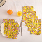 Set of four yellow and pink block print cotton napkins fanned out on a laid table
