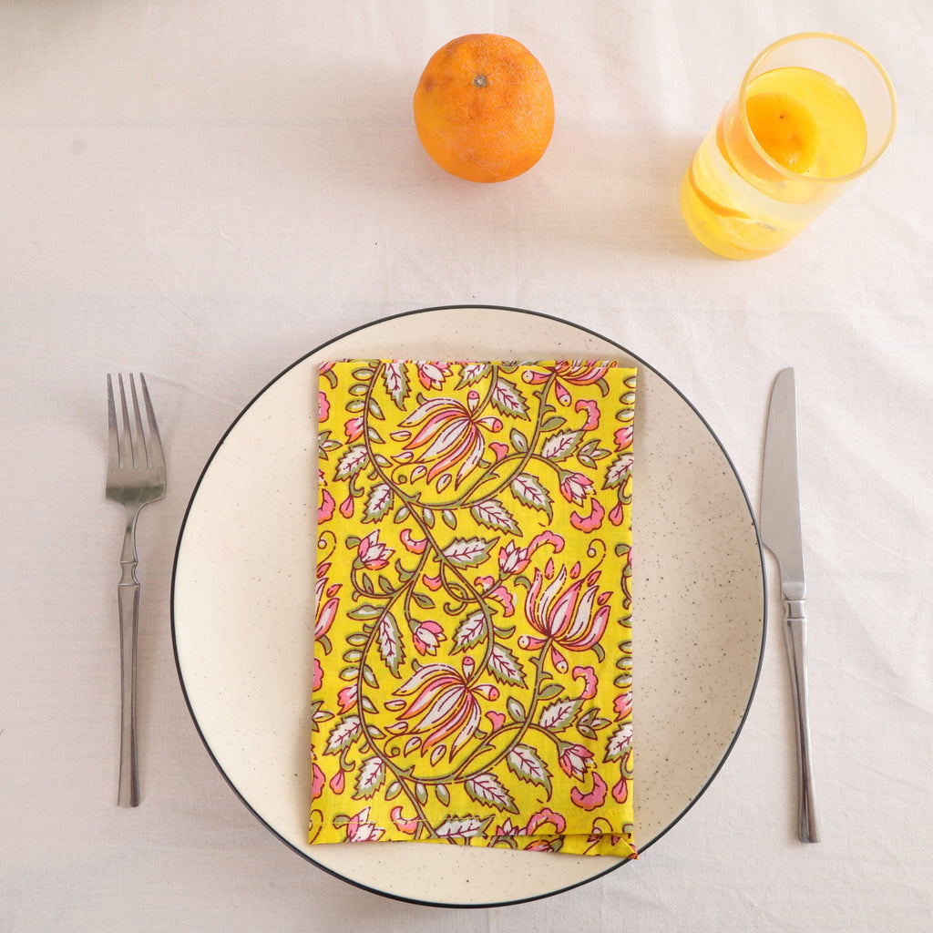 Yellow and pink paisley block print cotton napkin folded on a dinner plate