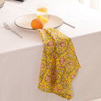 Yellow and pink paisley block print napkin draped over the edge of a table