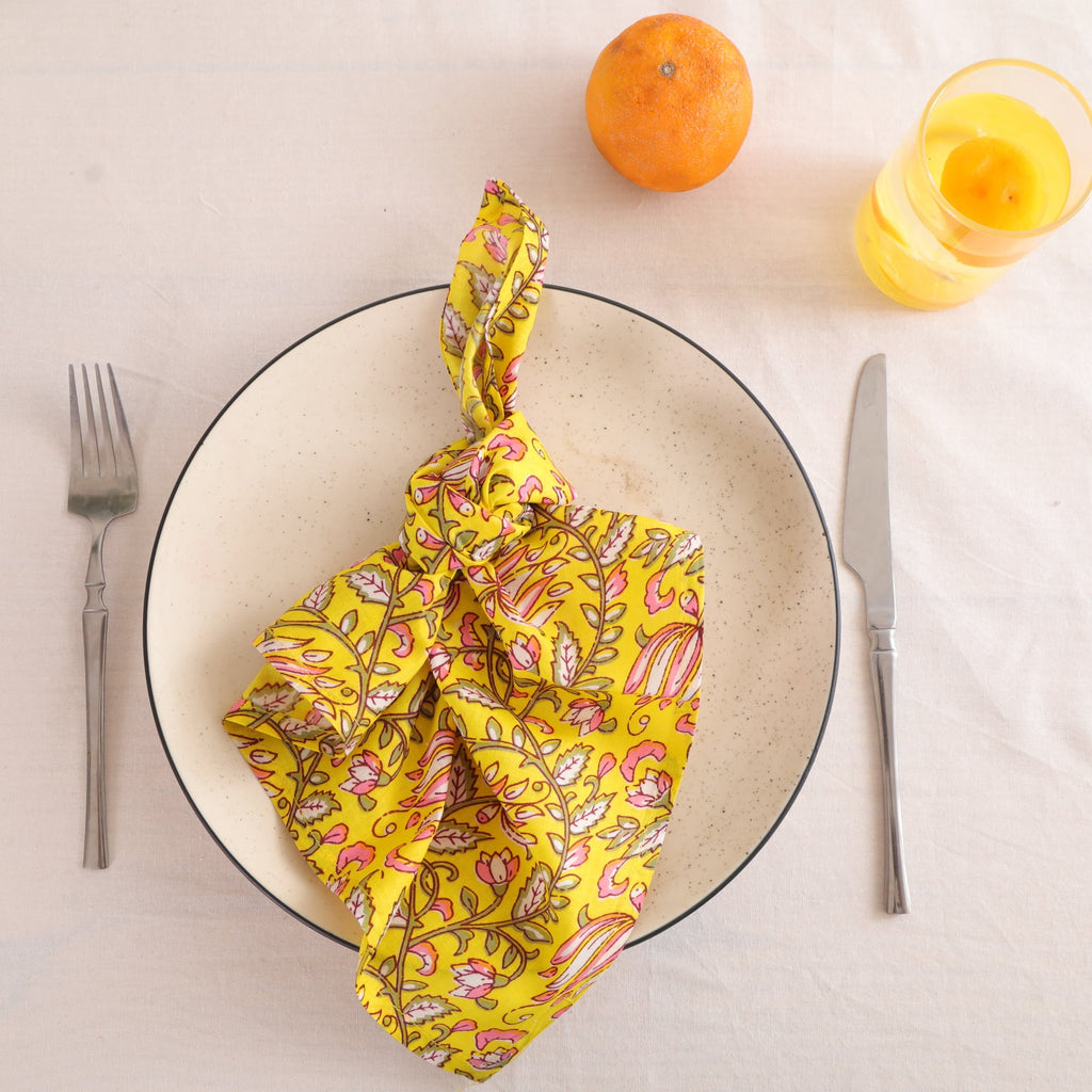 Yellow and pink paisley block print cotton napkin knotted on a plate