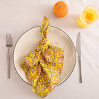 Yellow and pink paisley block print cotton napkin knotted on a plate