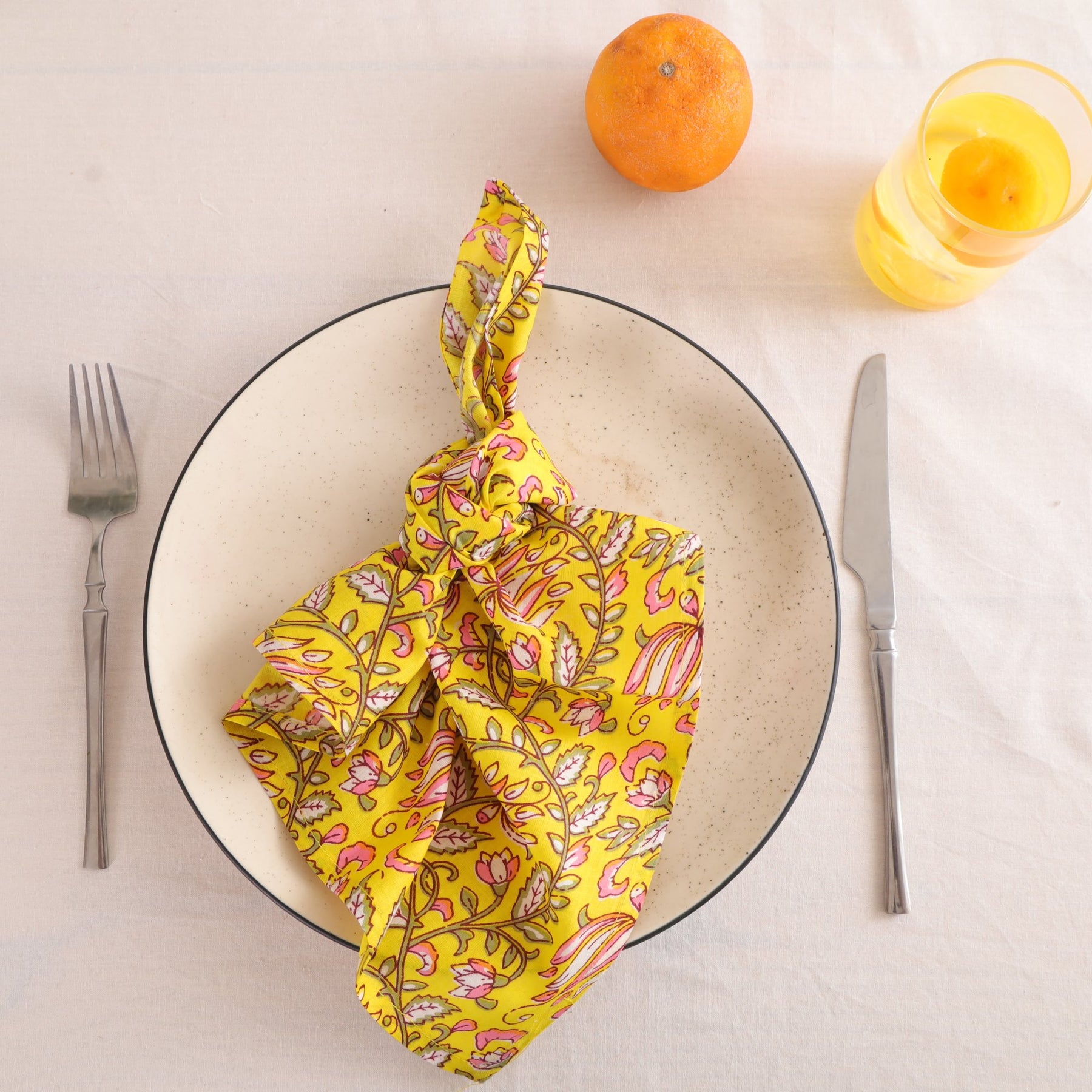 Yellow and pink paisley block print cotton napkin knotted on a plate