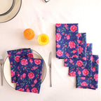 Set of four navy and pink block print cotton napkins fanned out on a laid table
