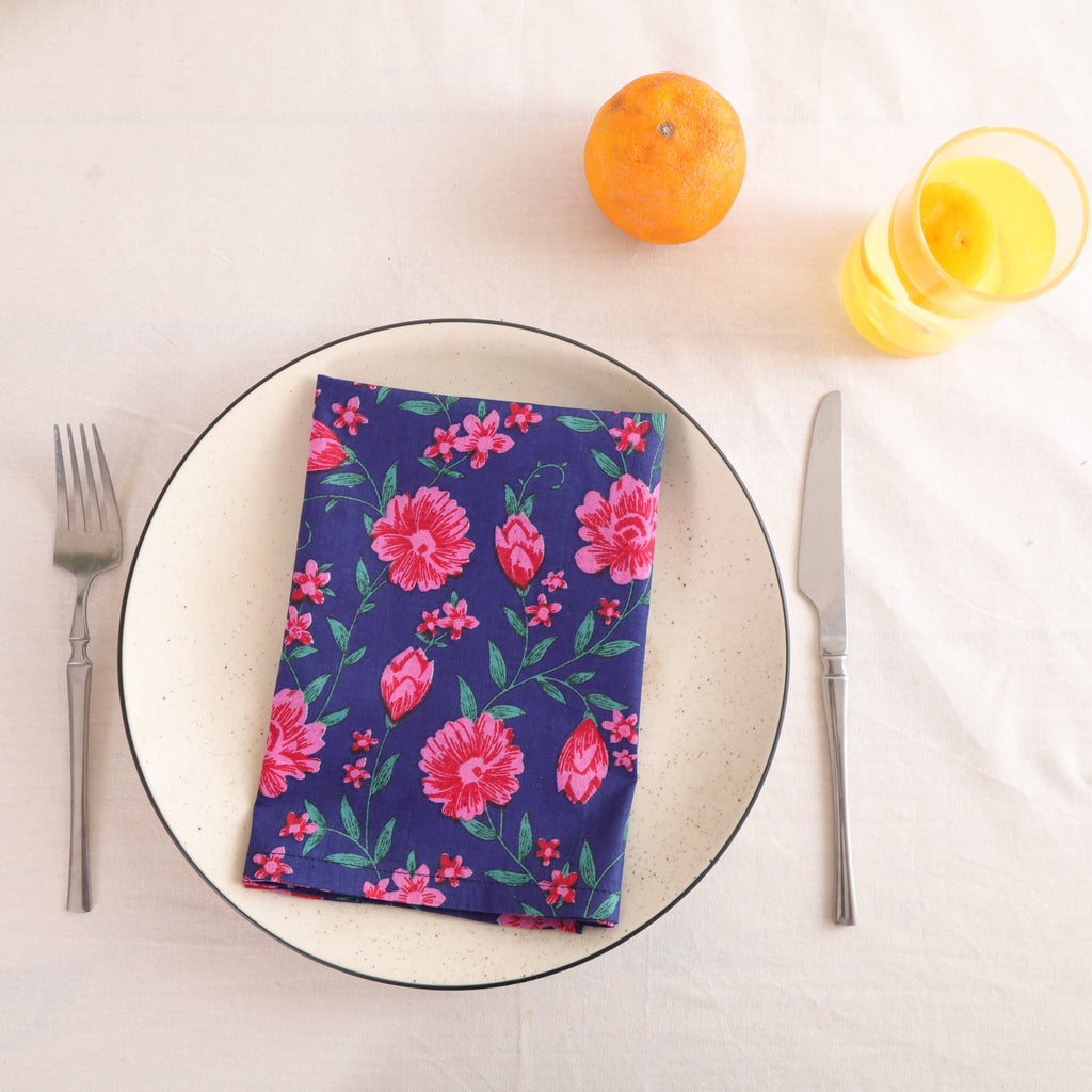Navy and pink block print cotton napkin folded on a dinner plate